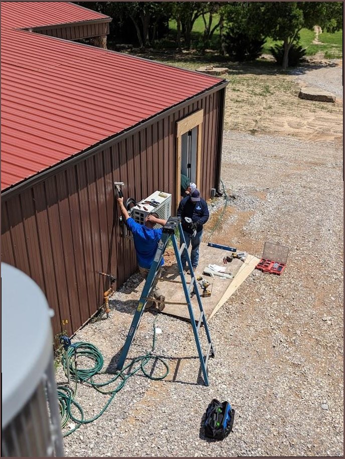 Two technicians installing wall-mounted AC unit